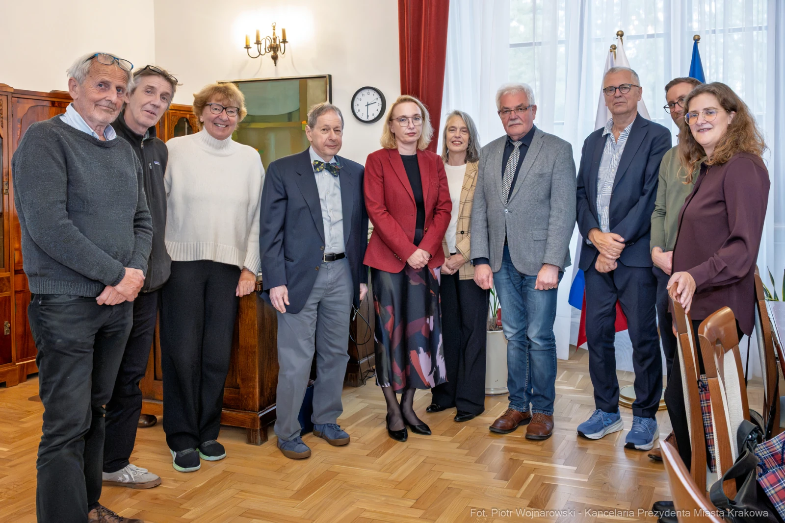 Grupa osób w formalnych strojach w sali z flagami i zegarem.  Autor: Piotr Wojnarowski