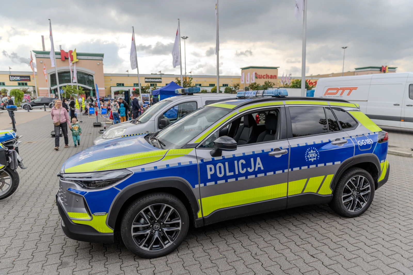 Radiowóz policyjny zaparkowany na parkingu, w tle ludzie i budynki.  Autor: Bogusław Świerzowski