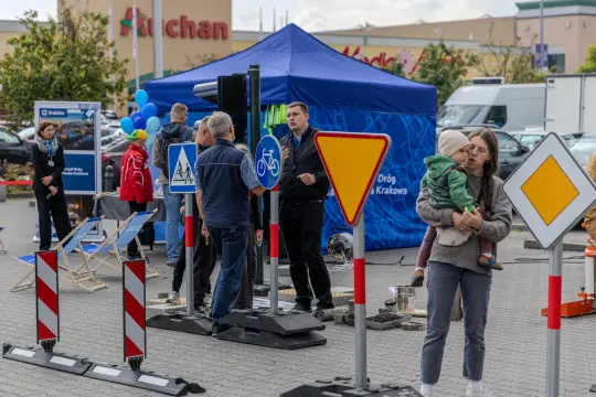 Wydarzenie edukacyjne z znakami drogowymi i uczestnikami w strefie ruchu.
