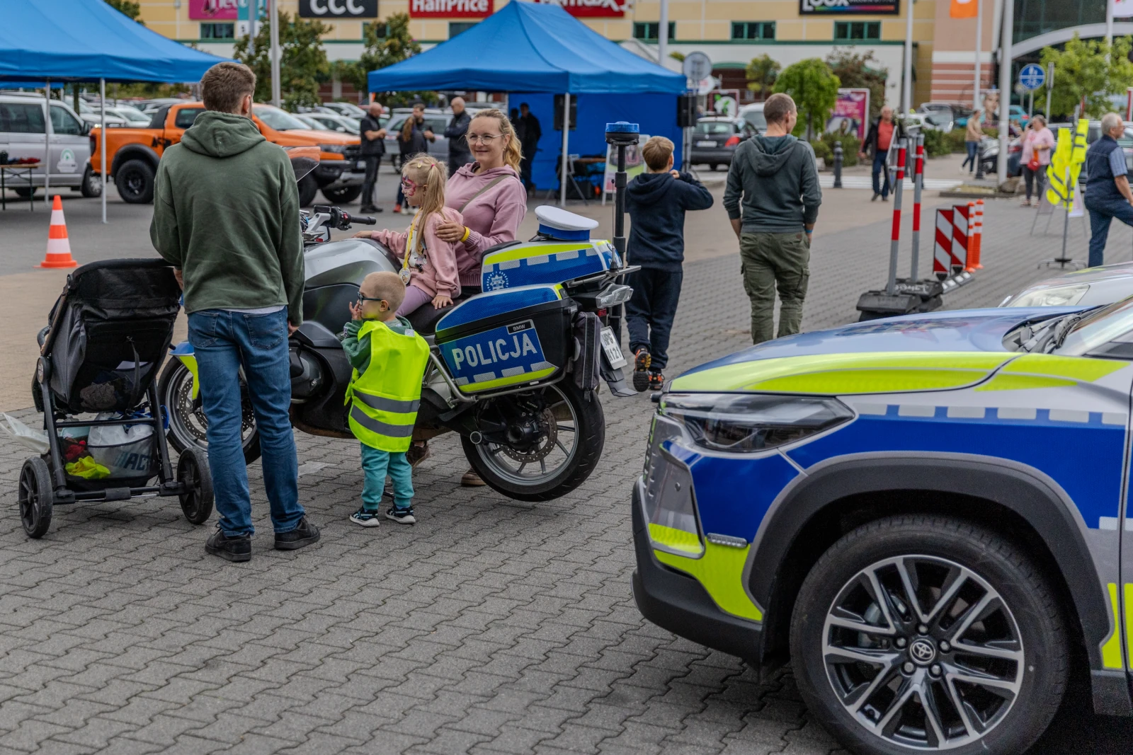 Dzieci i dorośli przy policyjnym motocyklu oraz radiowozie na terenie wydarzenia.  Autor: Bogusław Świerzowski