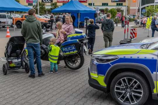 Dzieci i dorośli przy policyjnym motocyklu oraz radiowozie na terenie wydarzenia.
