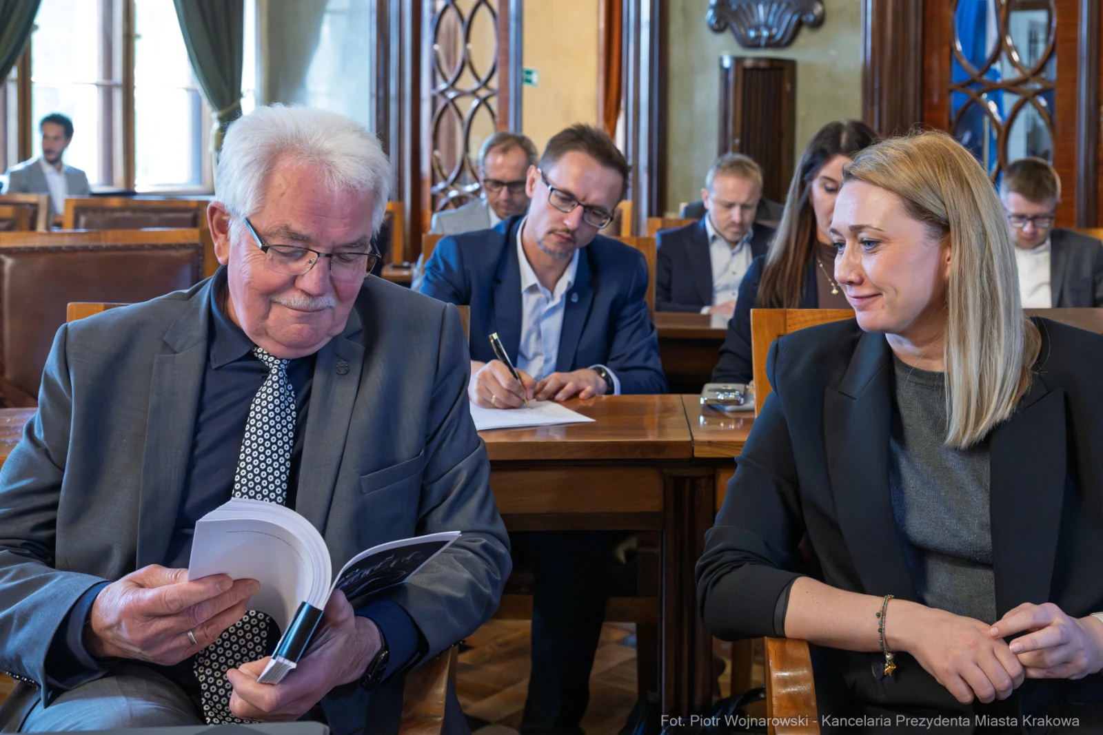Mężczyzna przegląda dokumenty, obok siedzi kobieta, w tle inni uczestnicy spotkania.  Autor: Piotr Wojnarowski