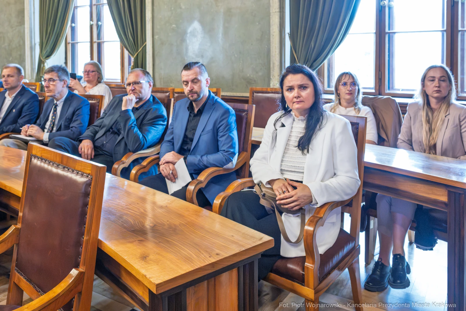Grupa osób siedzących przy drewnianych stołach w sali konferencyjnej.  Autor: Piotr Wojnarowski