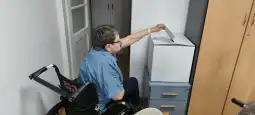Osoba na wózku inwalidzkim wrzucająca kartę do głosowania do urny.