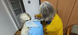 Dwie osoby w pomieszczeniu, jedna z nich pokazuje coś drugiej.