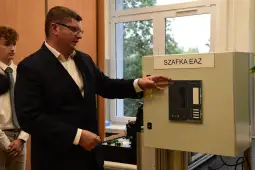 Mężczyzna w garniturze pokazuje panel sterujący szafki EAZ, obok stoi młody mężczyzna.