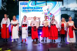 Grupa kobiet w tradycyjnych strojach śpiewa na scenie podczas festiwalu w Krakowie.