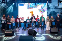 Uczestnicy wydarzenia na scenie, trzymający torby z nagrodami.