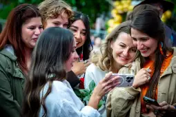 Grupa kobiet uśmiecha się, oglądając coś na telefonie.