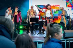 Muzycy w tradycyjnych strojach grają na instrumentach, jedna osoba trzyma flagę.