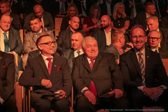 Grupa mężczyzn w garniturach siedzących na widowni podczas wydarzenia.