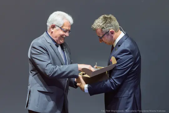 Dwaj mężczyźni wymieniają się prezentem na scenie.