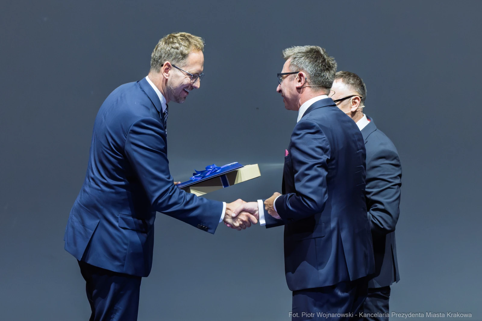 Mężczyźni w garniturach wymieniają uściski dłoni podczas ceremonii wręczenia nagrody.  Autor: Piotr Wojnarowski