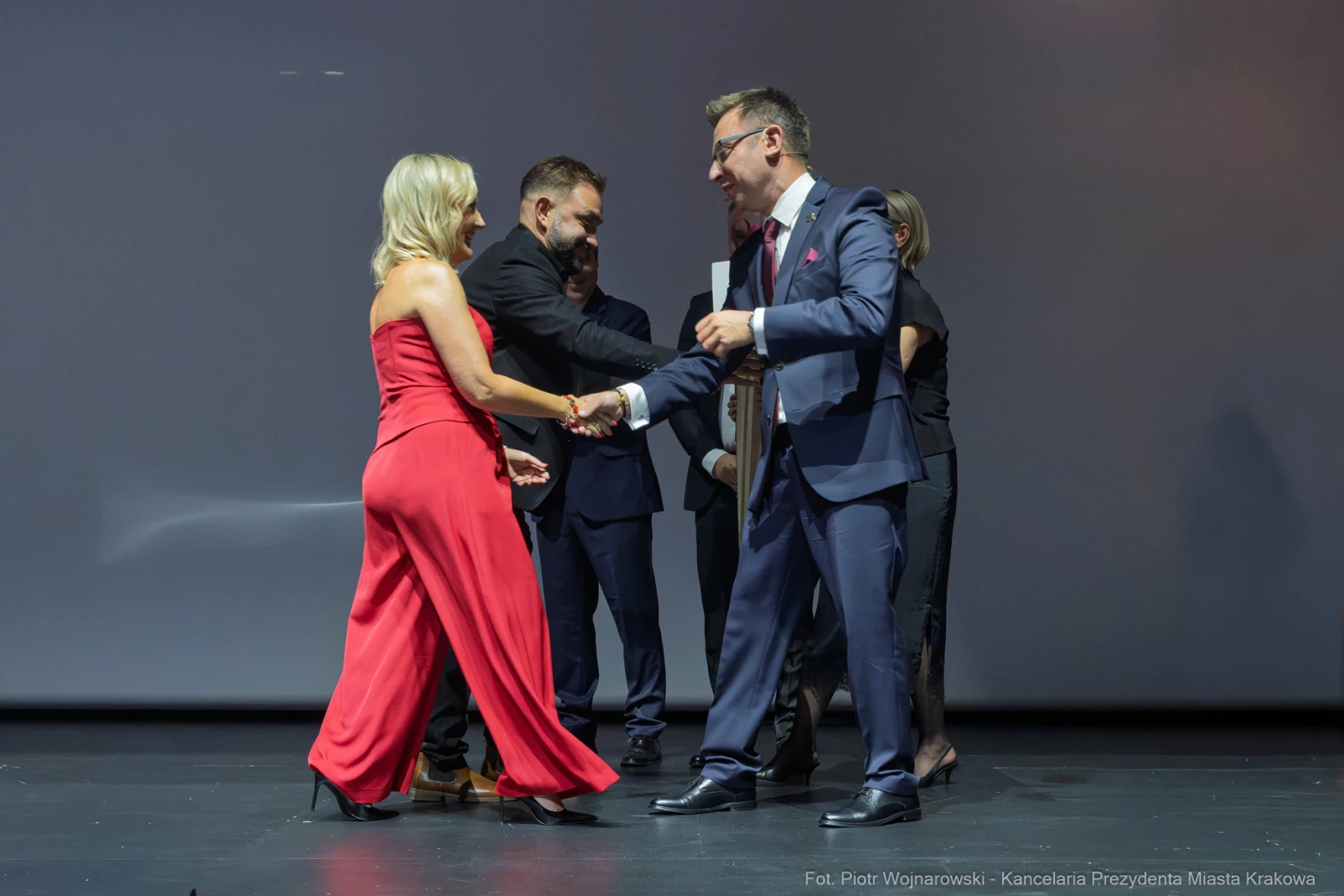 Uroczystość wręczenia nagrody, uściski dłoni, eleganckie stroje.  Autor: Piotr Wojnarowski
