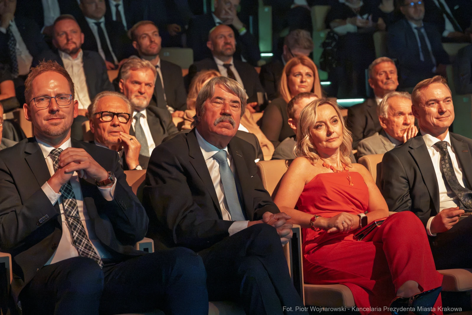 Grupa ludzi siedzących na widowni, uśmiechających się i słuchających wystąpienia.  Autor: Piotr Wojnarowski