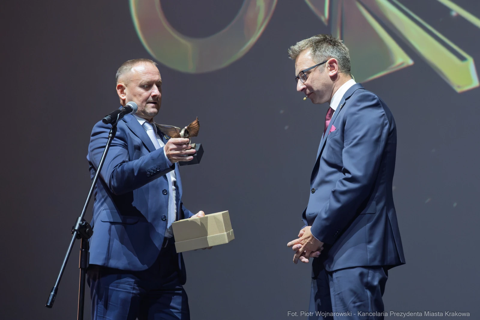 Mężczyzna wręcza nagrodę innemu mężczyźnie na scenie podczas uroczystości.  Autor: Piotr Wojnarowski