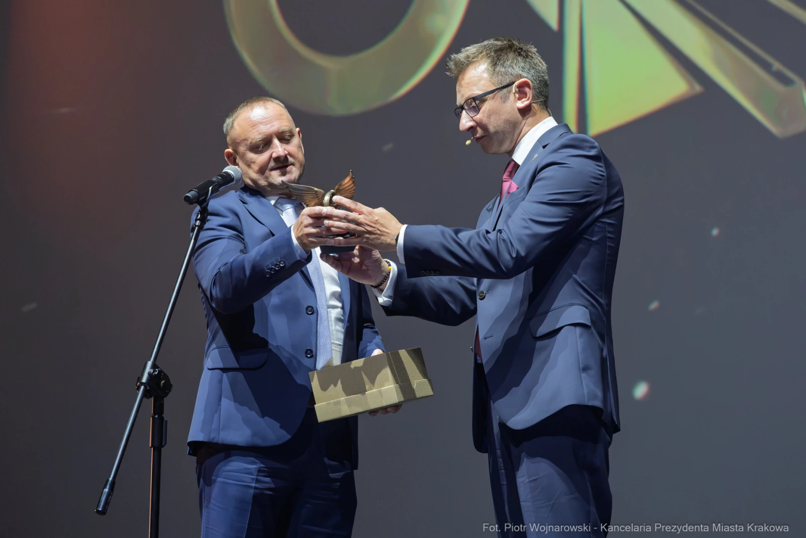 Wręczenie nagrody przez mężczyznę w garniturze drugiemu mężczyźnie z trofeum w ręku.  Autor: Piotr Wojnarowski