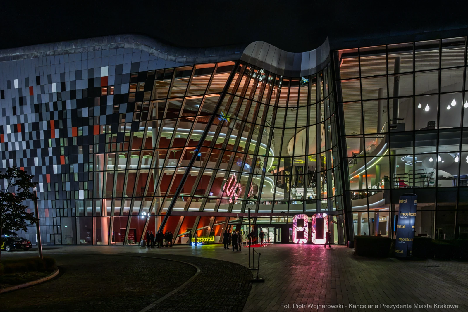 Nowoczesny budynek z kolorowymi iluminacjami, wejście z dużymi cyframi 60.  Autor: Piotr Wojnarowski