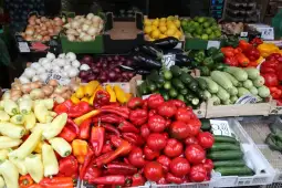 Kolorowe warzywa: papryka, cukinia, cebula, bakłażany i cytryny w straganach.