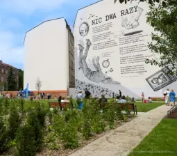 Murale z tekstem i ilustracjami oraz ludzie odpoczywający w parku.