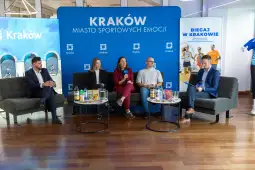 Panel dyskusyjny z uczestnikami na tle niebieskiego tła z napisem Kraków.