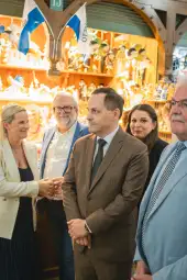 Grupa ludzi w eleganckich strojach, stojących w sklepie z rękodziełem.