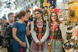Kobiety w tradycyjnych strojach ludowych wśród straganów z pamiątkami.