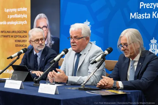 Trzech mężczyzn siedzi przy stole, omawiając temat zdrowia i edukacji.