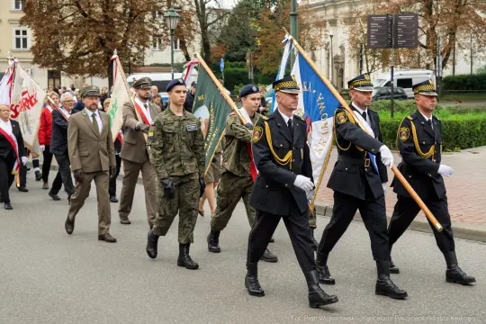 Marsz z flagami, uczestnicy w mundurach wojskowych i policyjnych.