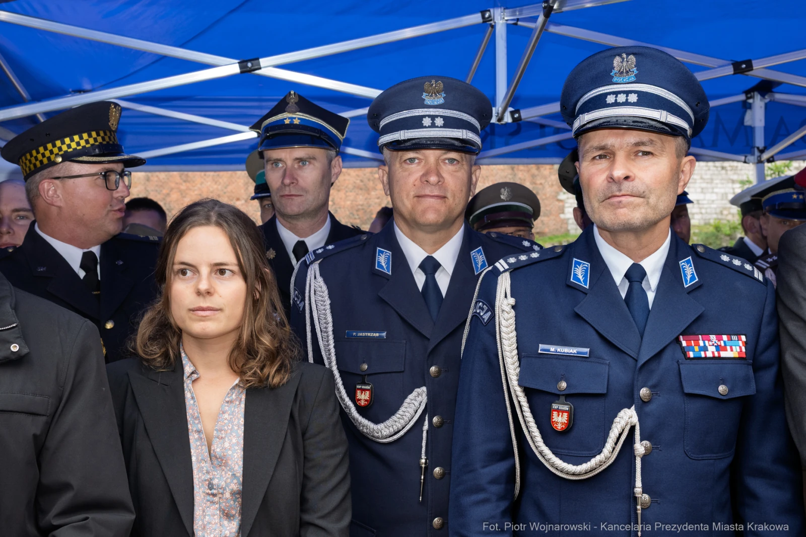 Grupa mężczyzn w mundurach policyjnych oraz kobieta w eleganckim stroju.  Autor: Piotr Wojnarowski