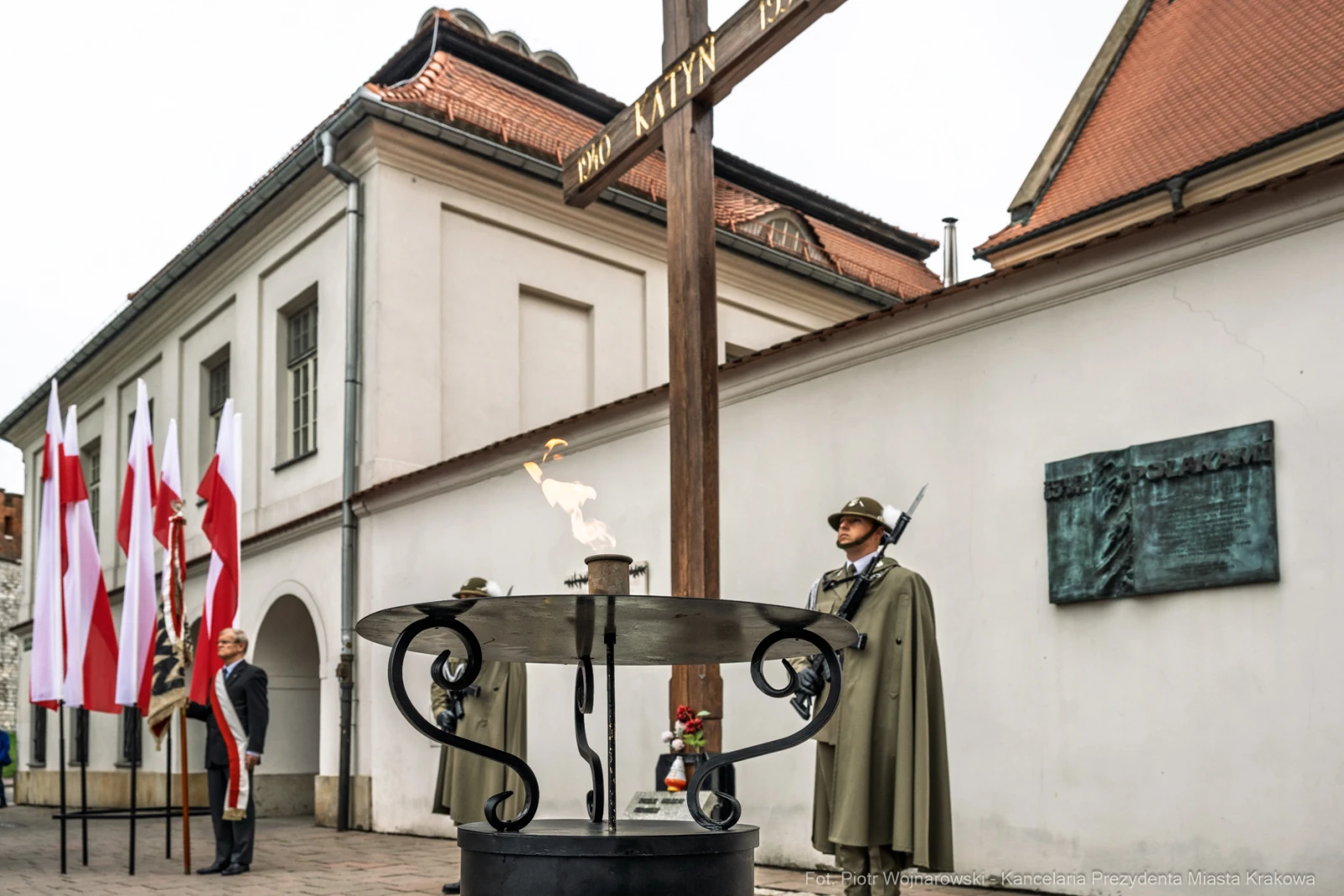 Pomnik upamiętniający ofiary Katynia z wartownikami i zniczem. Flagi Polski w tle.  Autor: Piotr Wojnarowski