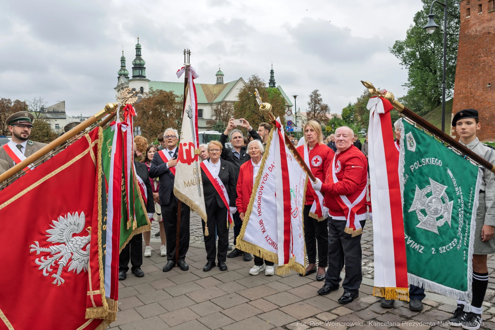 Uczestnicy ceremonii z flagami i sztandarami w historycznym otoczeniu.  Autor: Piotr Wojnarowski