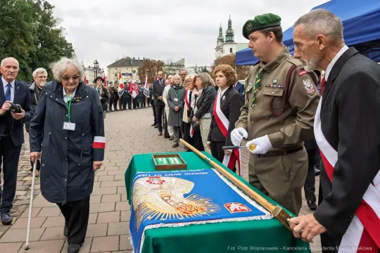 Uroczystość z udziałem wojskowych i cywilnych uczestników, z flagami i sztandarem.
