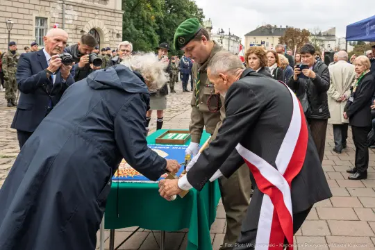 Uroczystość z udziałem wojskowych i lokalnych działaczy, podpisywanie dokumentów.