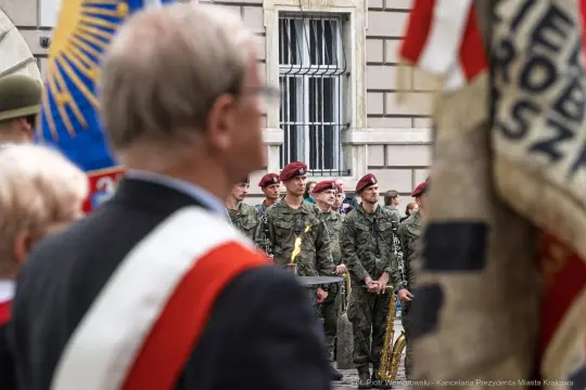 Uroczystość wojskowa z żołnierzami w mundurach i sztandarami.