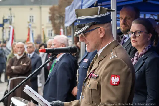 Mężczyzna w mundurze wojskowym przemawia podczas uroczystości z udziałem tłumu.