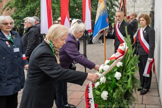 Uczestnicy ceremonii składają kwiaty w hołdzie.