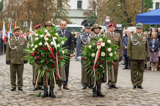Uroczystość złożenia kwiatów przez żołnierzy i oficjeli. W tle zgromadzeni ludzie.