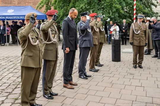 Ceremonia wojskowa z salutującymi żołnierzami i oficjelami.