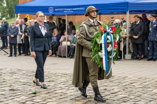 Ceremonia składania wieńca przez żołnierza i kobietę przed namiotem Instytutu Pamięci Narodowej.
