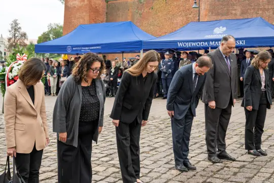 Uczestnicy ceremonii składają hołd, pochylając głowy.