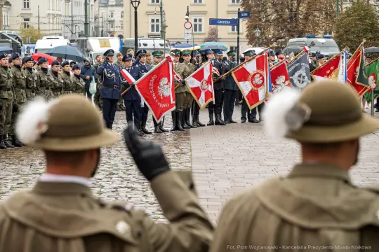 Ceremonia wojskowa z flagami i żołnierzami w mundurach na placu.