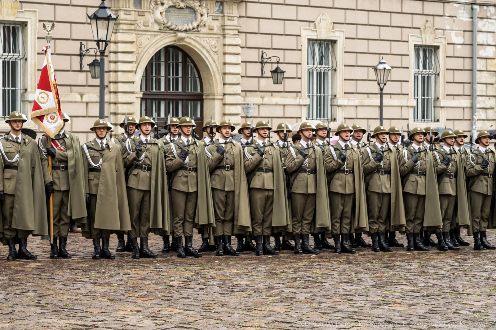 Żołnierze w mundurach stoją w szeregu, trzymając flagę.  Autor: Piotr Wojnarowski