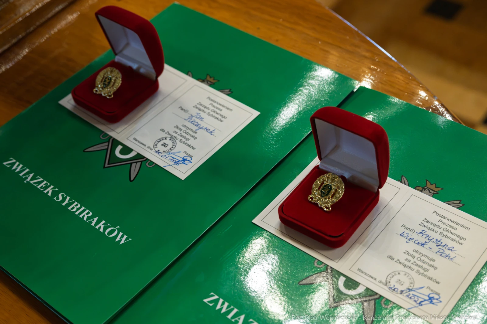 Dwa czerwone pudełka z odznaczeniami na zielonych dokumentach.  Autor: Piotr Wojnarowski