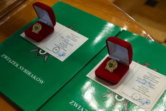 Dwa czerwone pudełka z odznaczeniami na zielonych dokumentach.