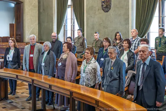 Grupa osób stojących w sali, uczestniczących w wydarzeniu.