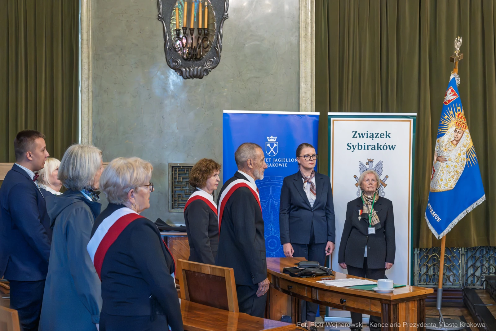 Ceremonia wręczenia odznaczeń członkom Związku Sybiraków w sali z flagami i emblematami.  Autor: Piotr Wojnarowski