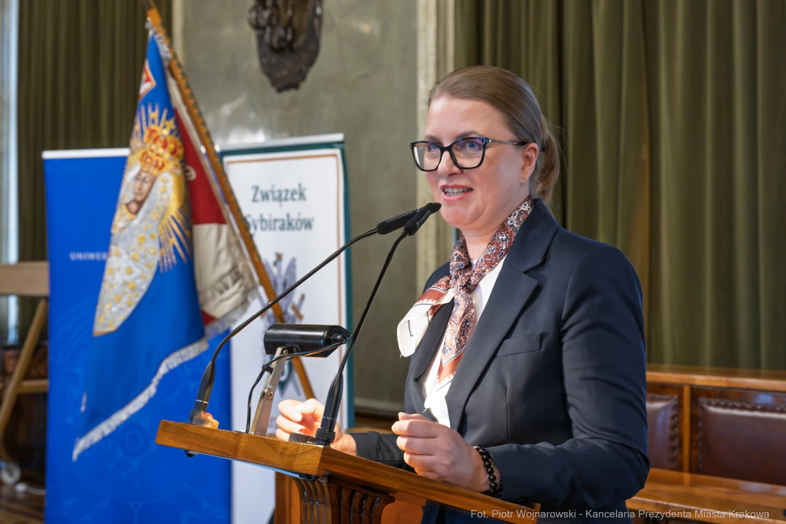 Kobieta przemawia z mównicy, w tle flagi i banery.  Autor: Piotr Wojnarowski