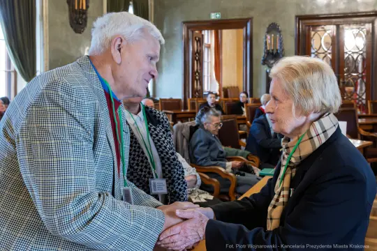 Spotkanie dwóch osób w eleganckim wnętrzu, wymiana uścisków dłoni.