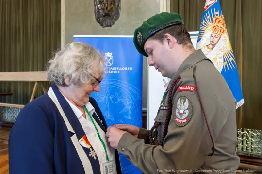 Wręczenie odznaczenia przez żołnierza kobiecie w mundurze i odznakach.